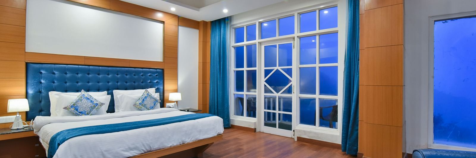 A large bed placed in front of the sofas in Luxury Room with Balcony at DLS Highland Resort and Spa, Mussoorie.